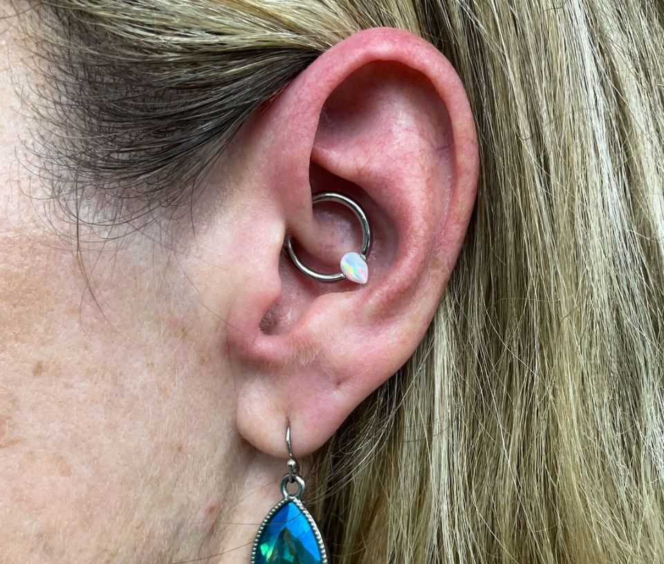 A close-up of a woman's ear with a piercing and earrings