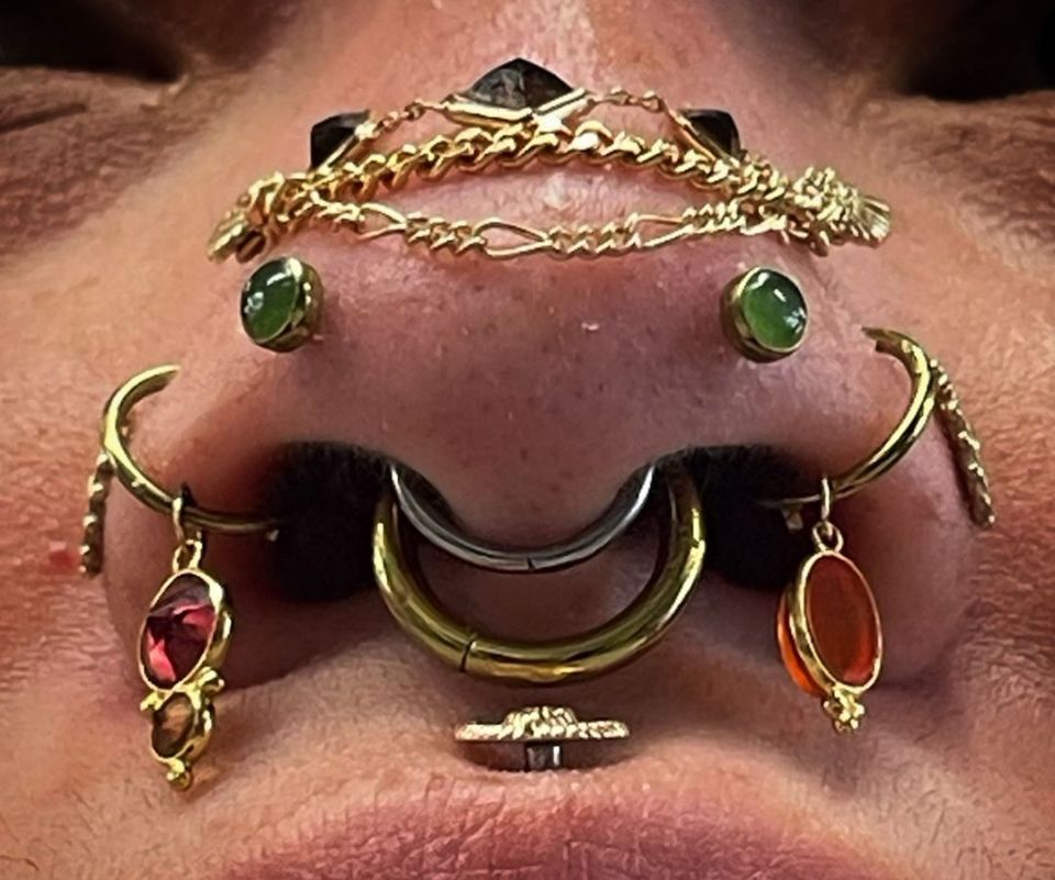 A close-up of a woman's nose with a lot of piercings