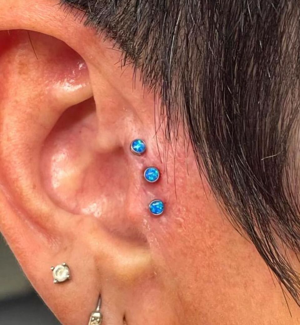 A close-up of a person's ear with three piercings.