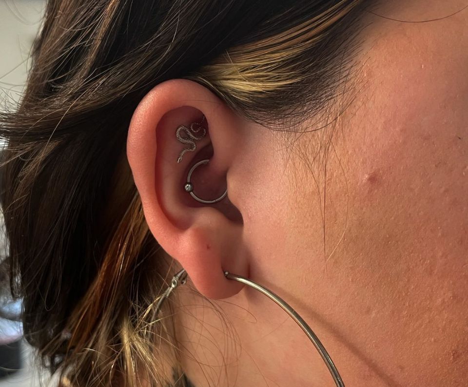 A close-up image of a woman's ear with multiple piercings