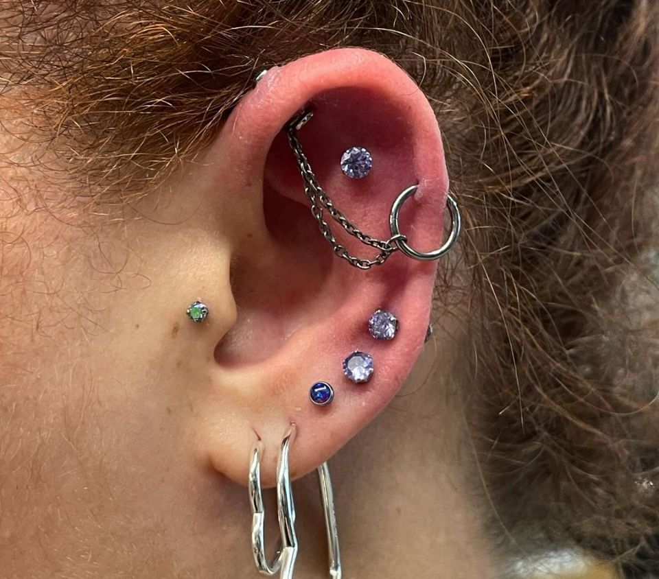 A close-up picture of a woman's ear with multiple piercings.