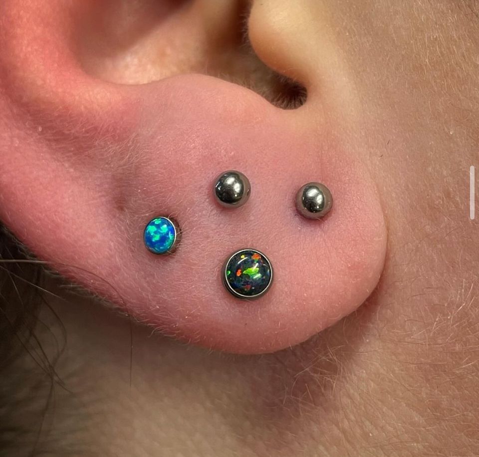A close-up of a person's ear with three earrings.