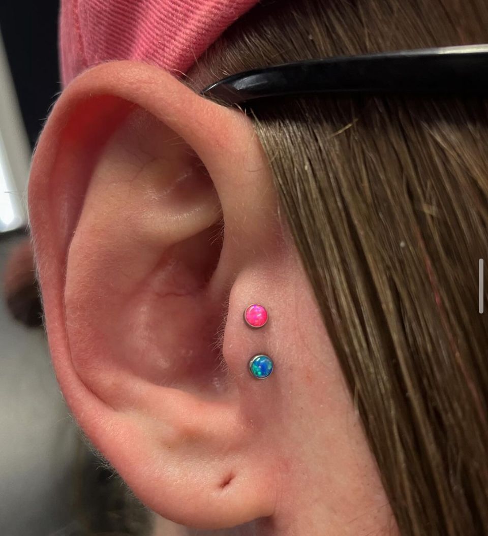 A close-up of a person's ear with two piercings.