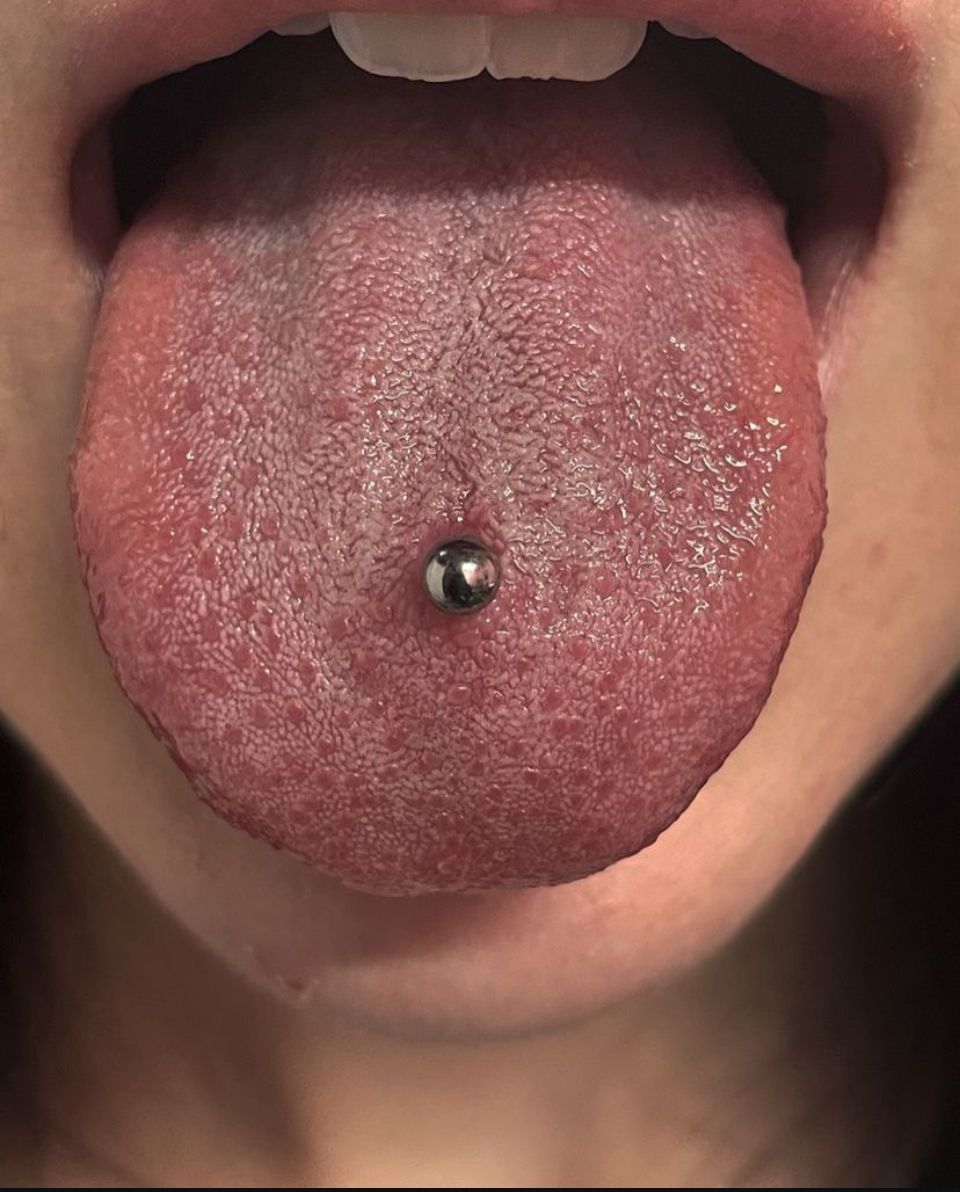 A close-up of a woman's tongue with a piercing in it.
