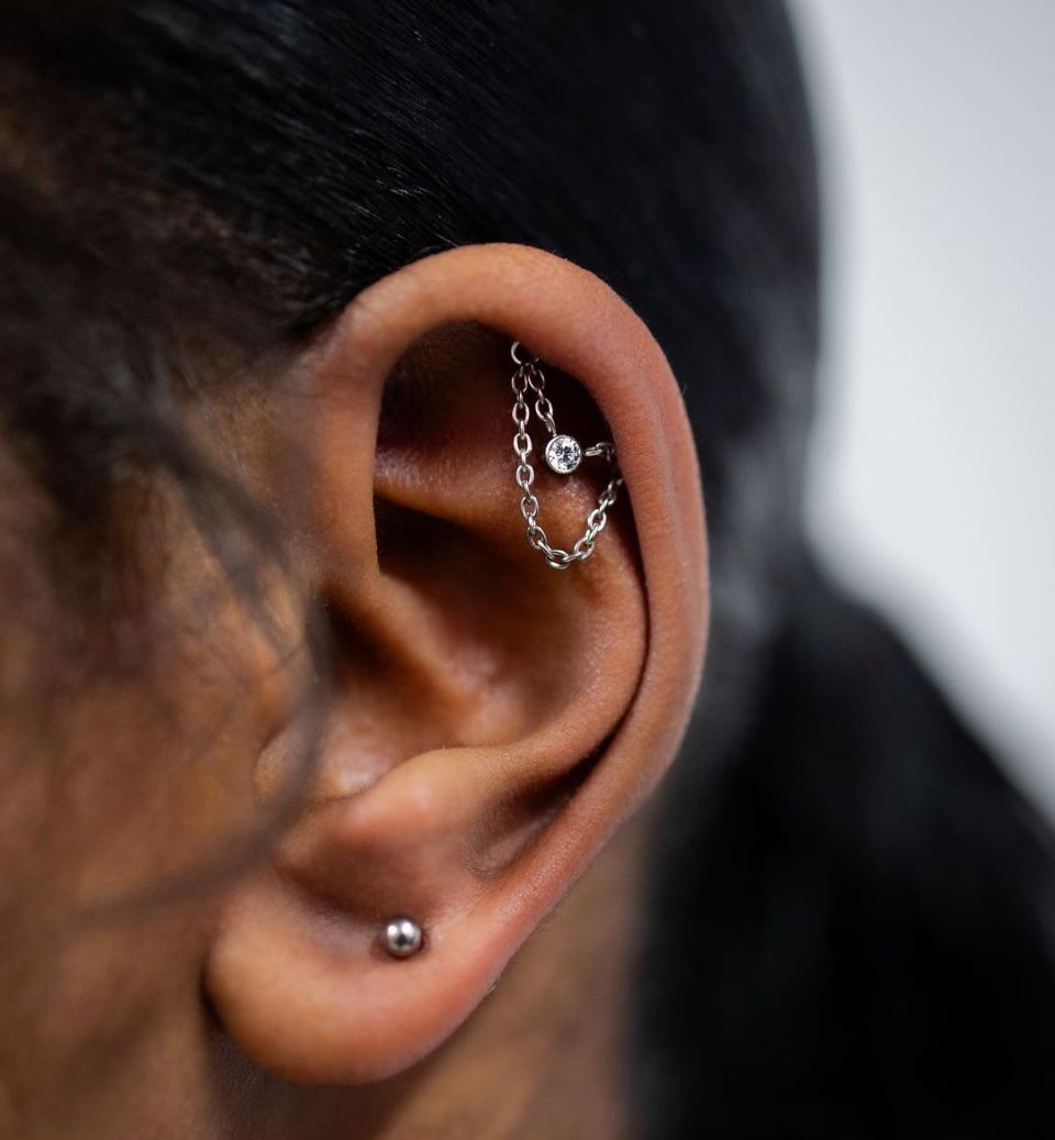A close-up of a woman's ear with earrings and a chain
