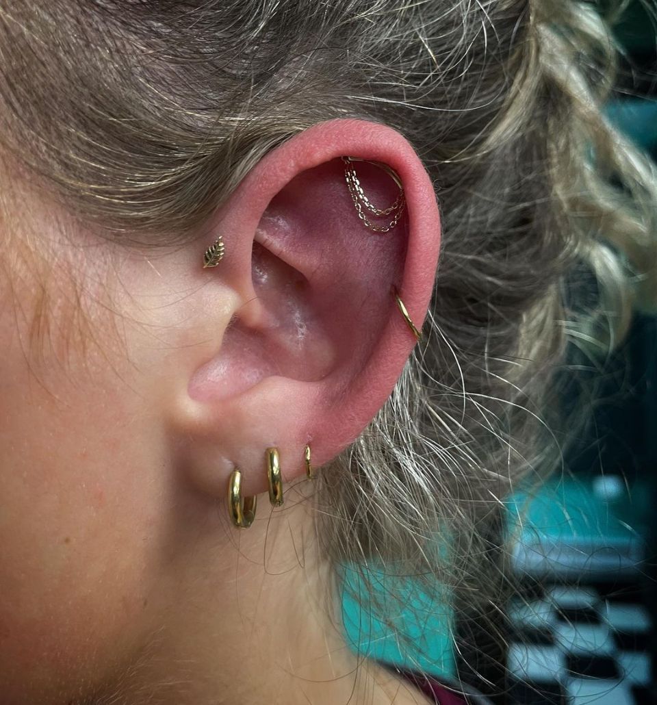A close-up of a woman's ear with multiple piercings.