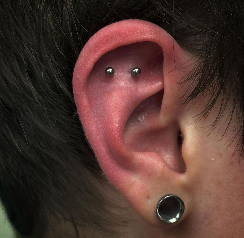 A close-up of a person's ear with piercings