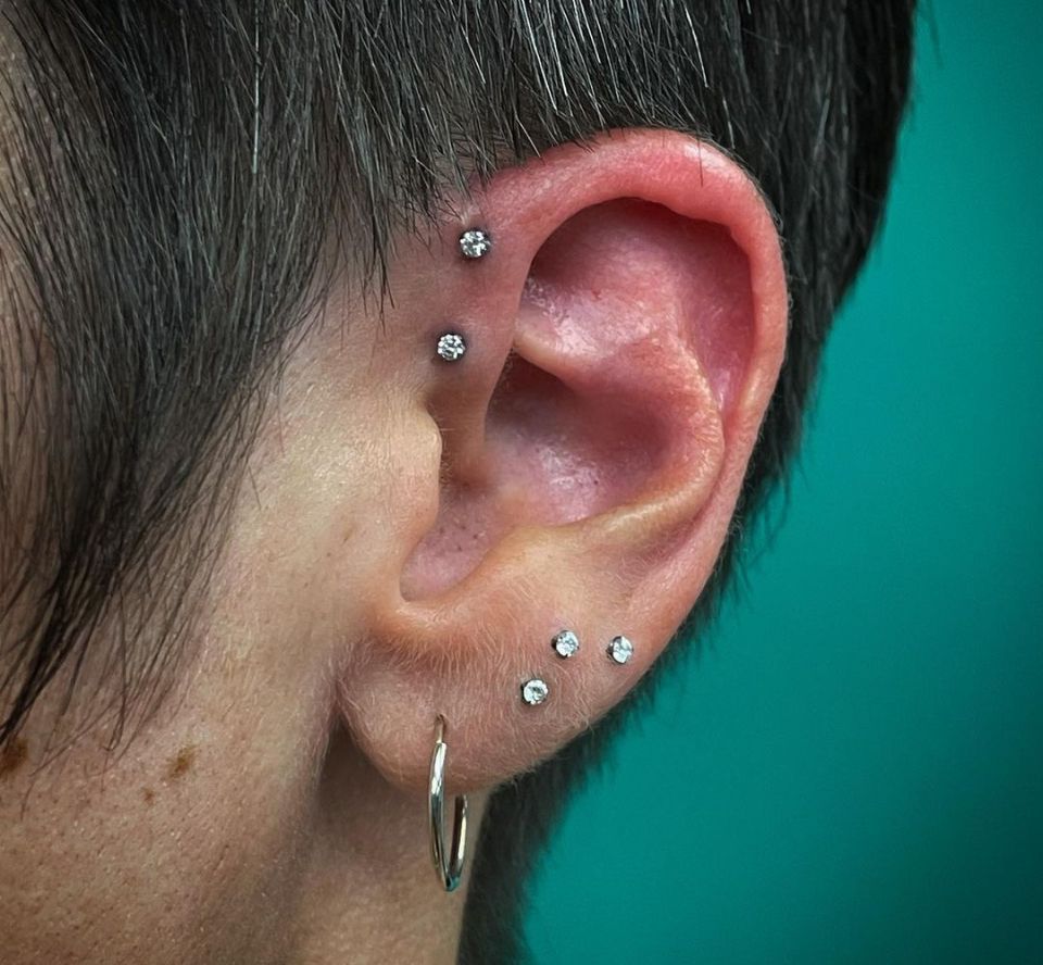 A close-up of a woman's ear with multiple piercings