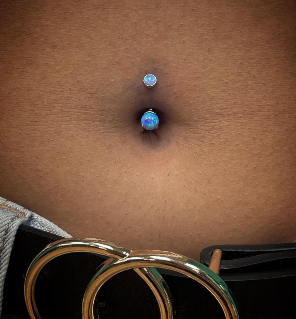 A close-up of a woman's belly with a belly button ring.