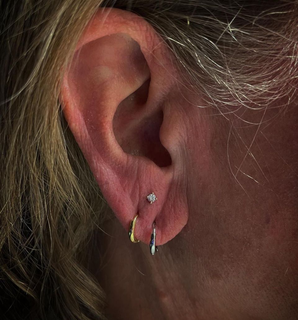 A close-up of a woman's ear with multiple piercings