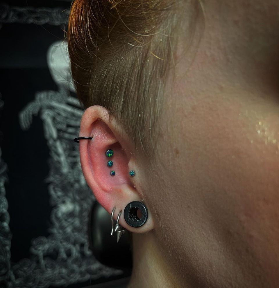 A close-up of a person's ear with multiple piercings