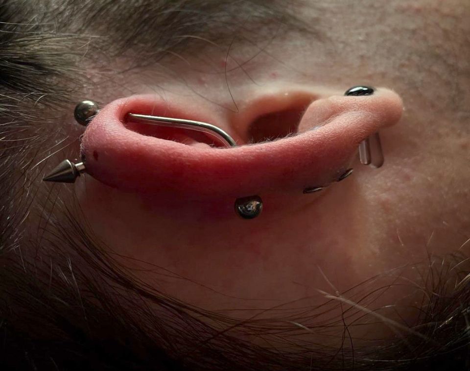 A close-up of a woman's ear with multiple piercings