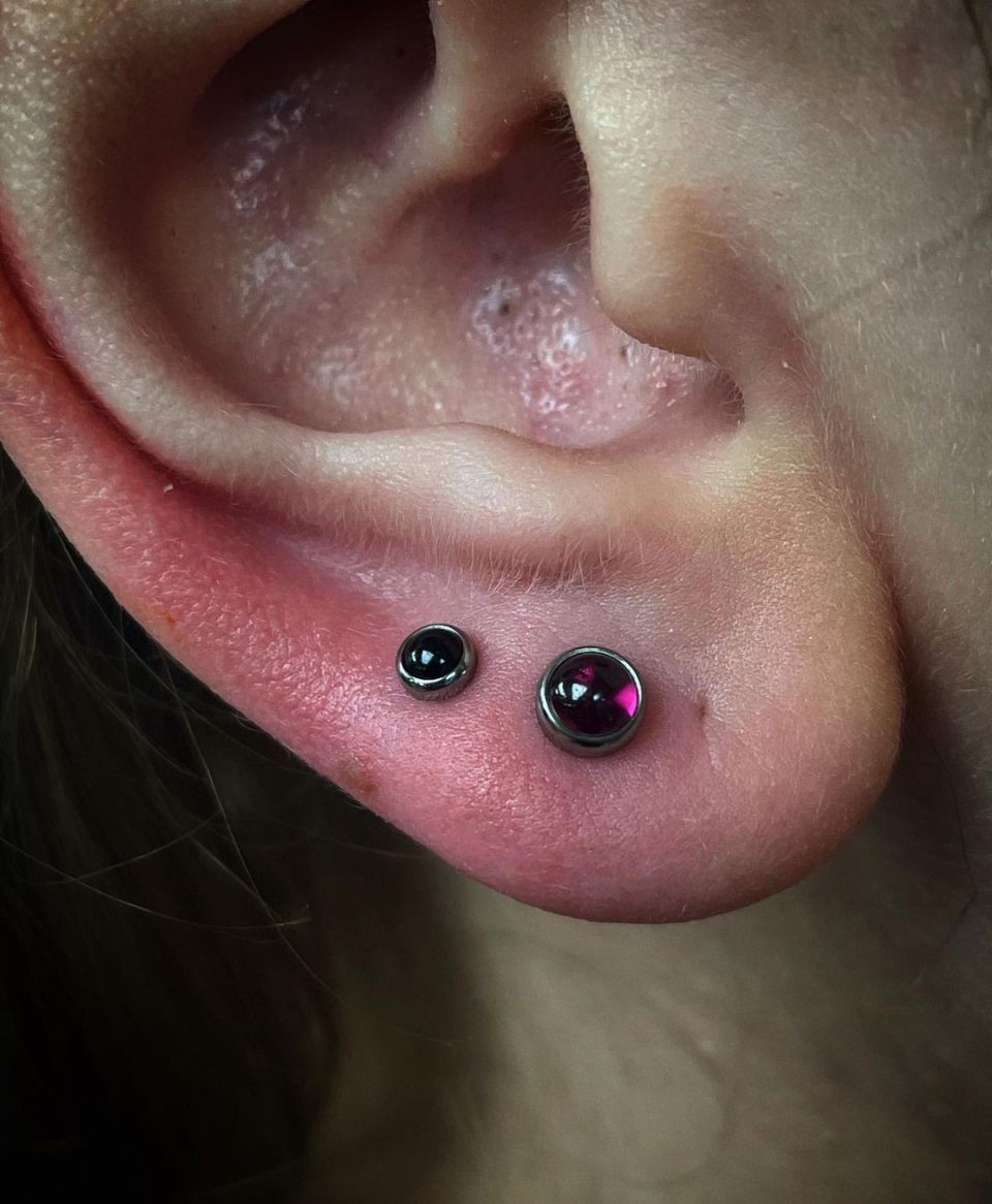 A close-up of a woman's ear with two earrings in it.