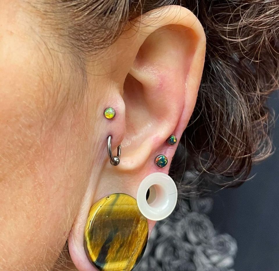 A close-up of a woman's ear with multiple piercings