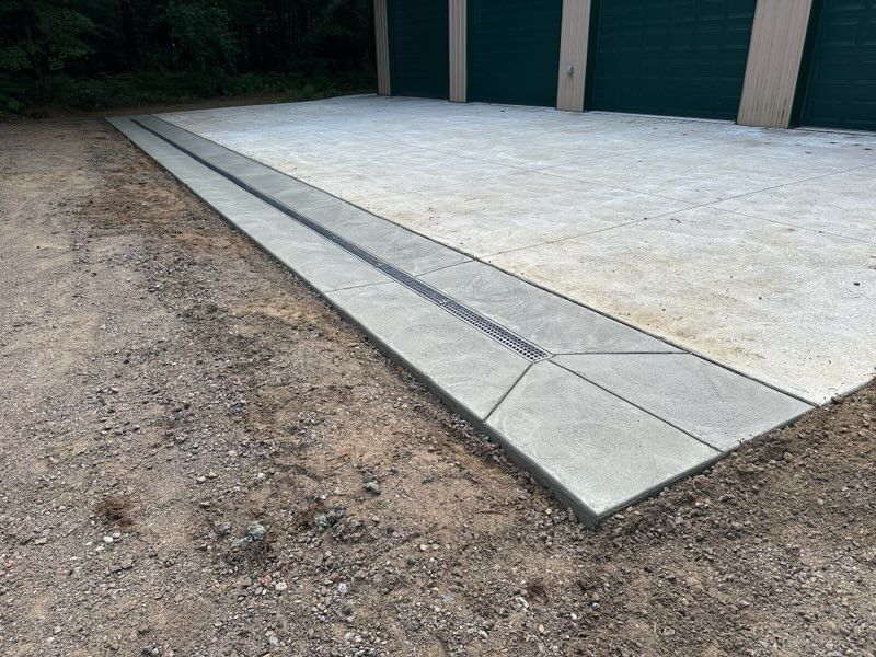 Concrete driveway slab beside a dirt lot, with a sloped curb ramp at the edge.