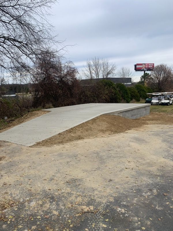 a concrete driveway leading to a building with a billboard in the background