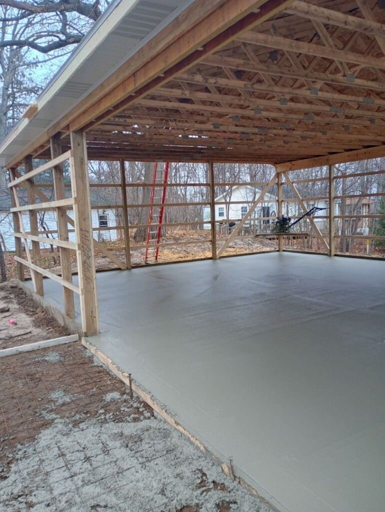 a garage under construction with a concrete floor and a wooden roof