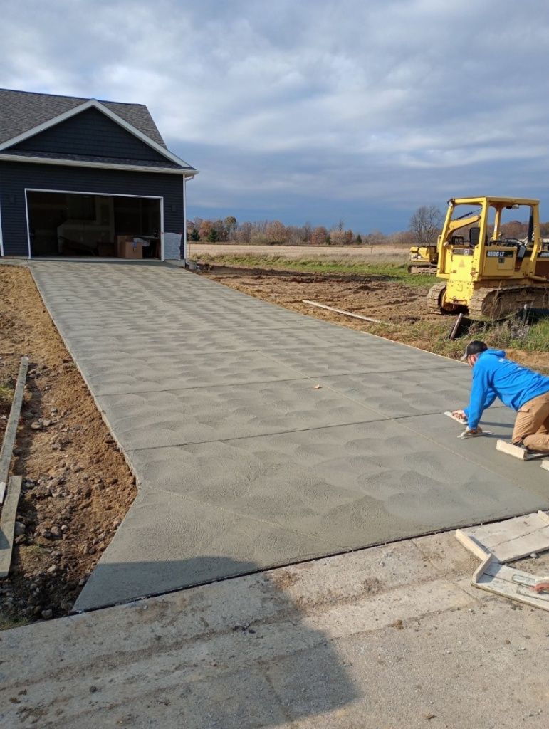 a man is laying concrete in a driveway in front of a house