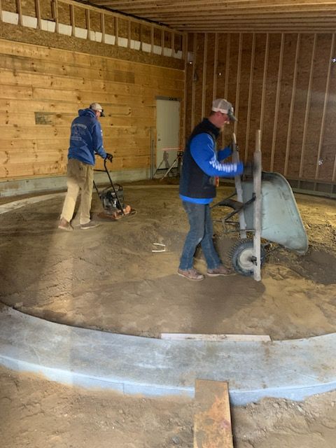 two men are working on a concrete floor in a building