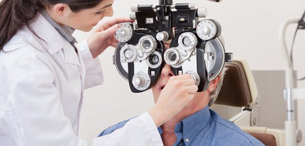 An old man having an eye checkup using a phoropter