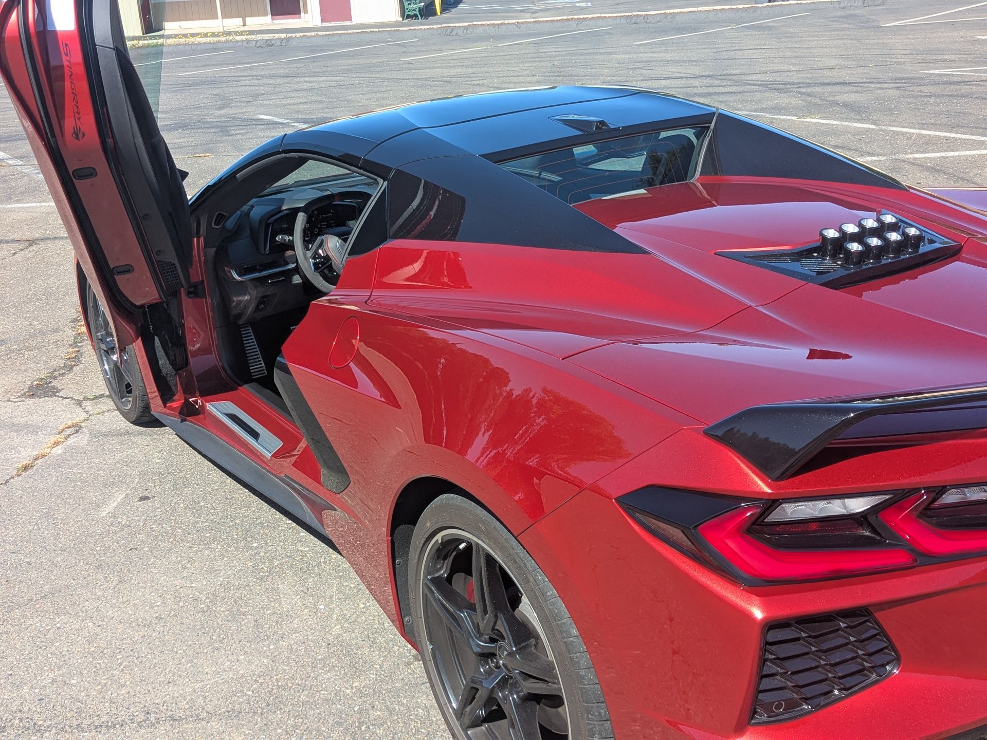 A sports car with the door open is parked in a parking lot