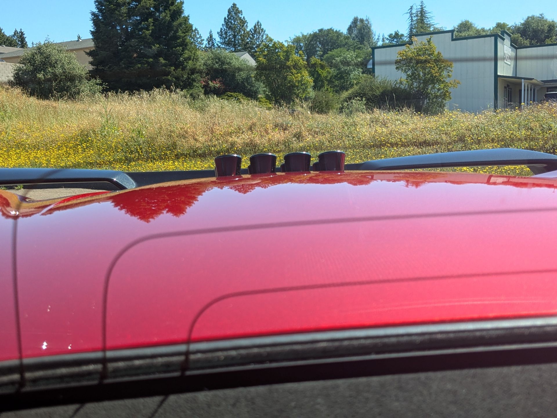 A red car is parked in front of a field