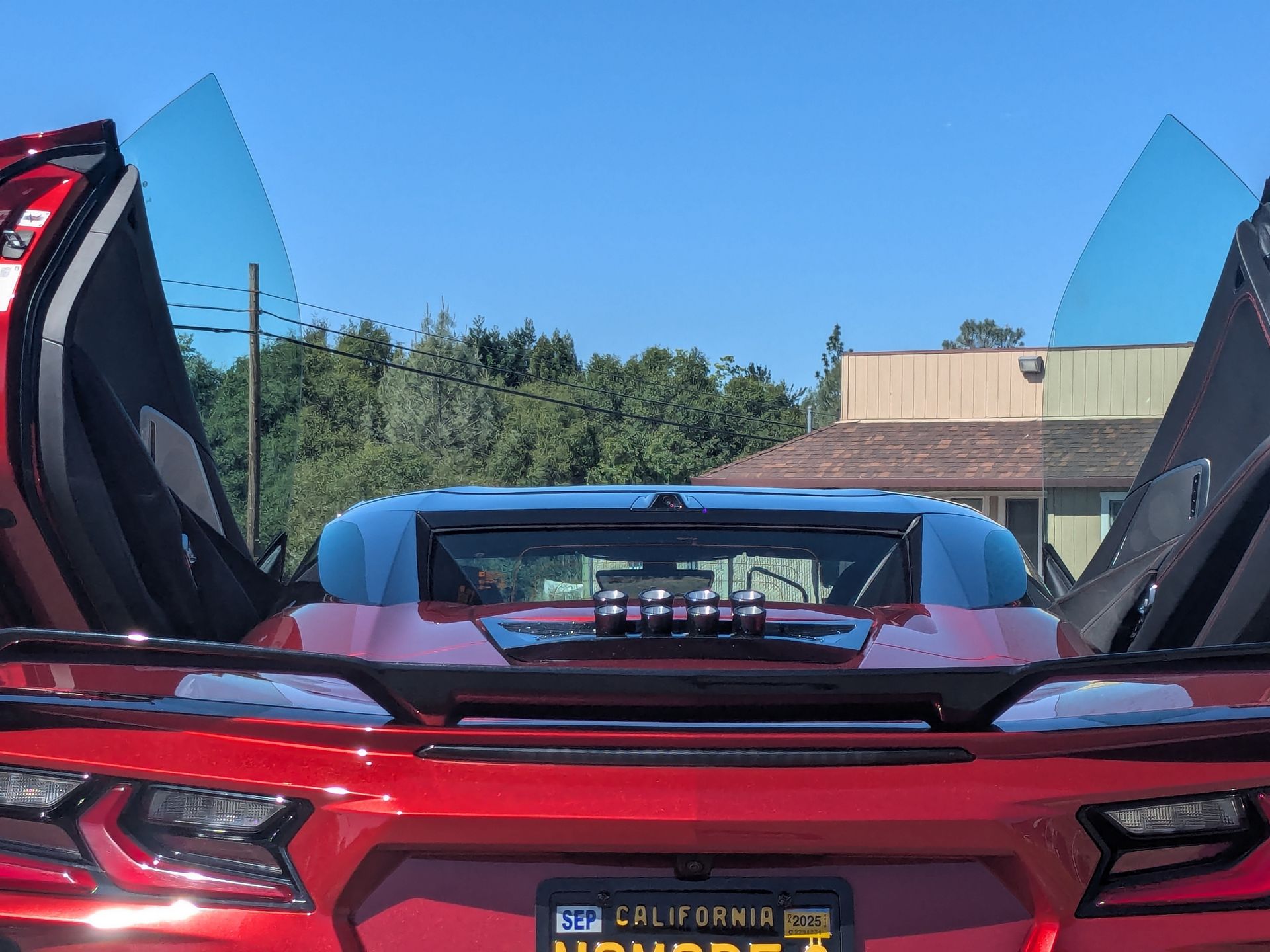 A red sports car with the trunk open and a California license plate