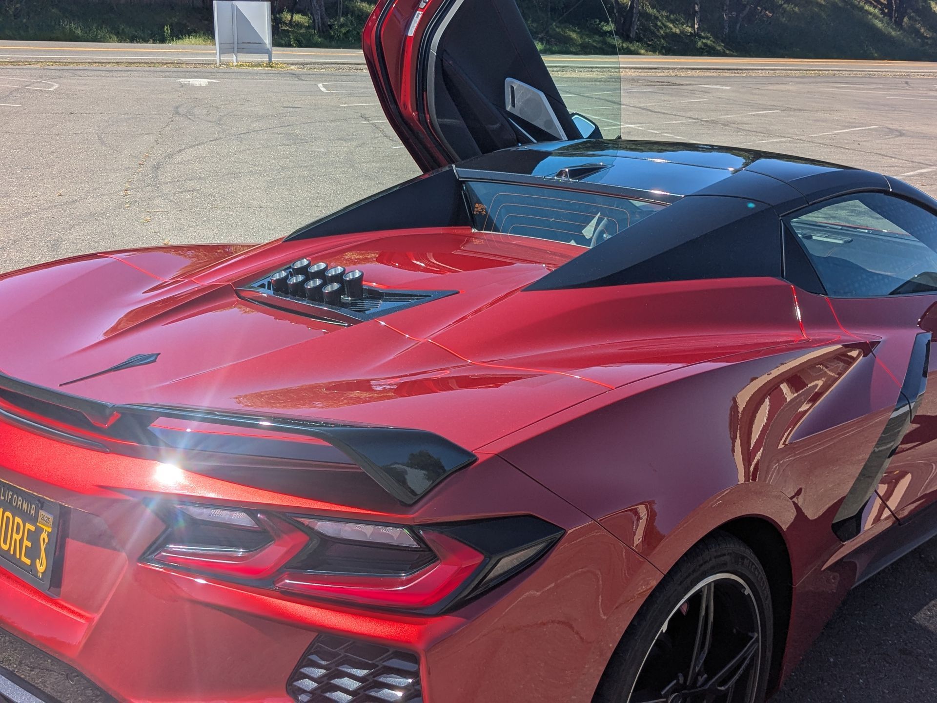 A red sports car with the hood open is parked in a parking lot