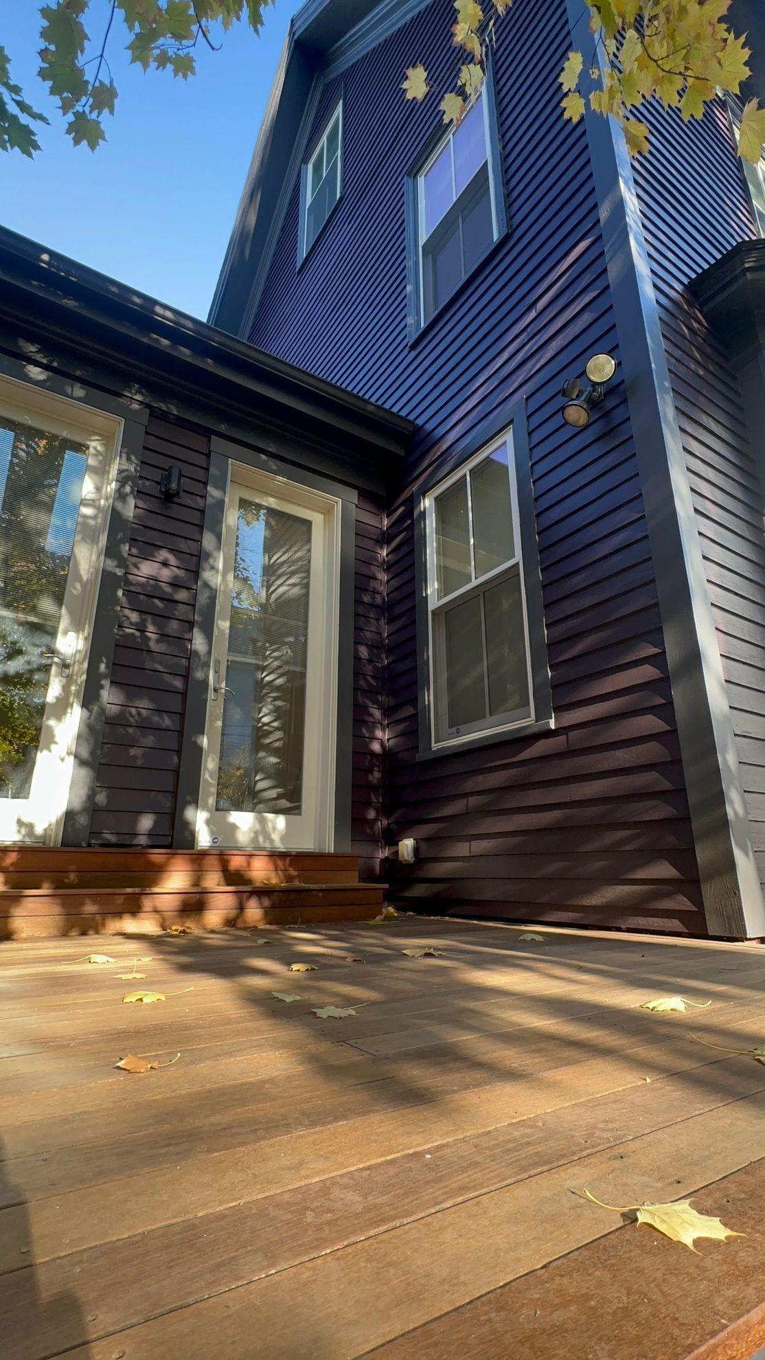 Brown wooden deck and siding of a two-story building on a sunny day.