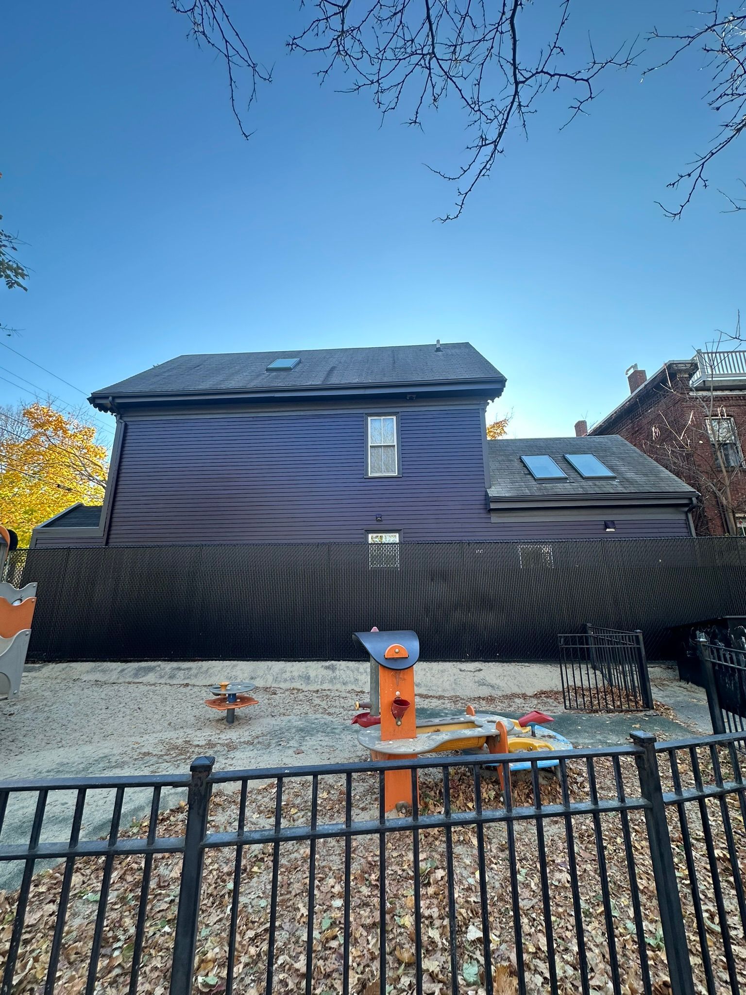 Backyard with dark purple building, black fence, and playground equipment.