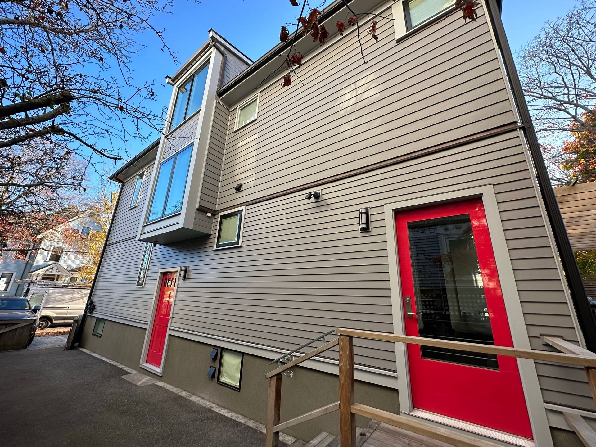 Modern gray building with red doors and large windows; wood ramp.