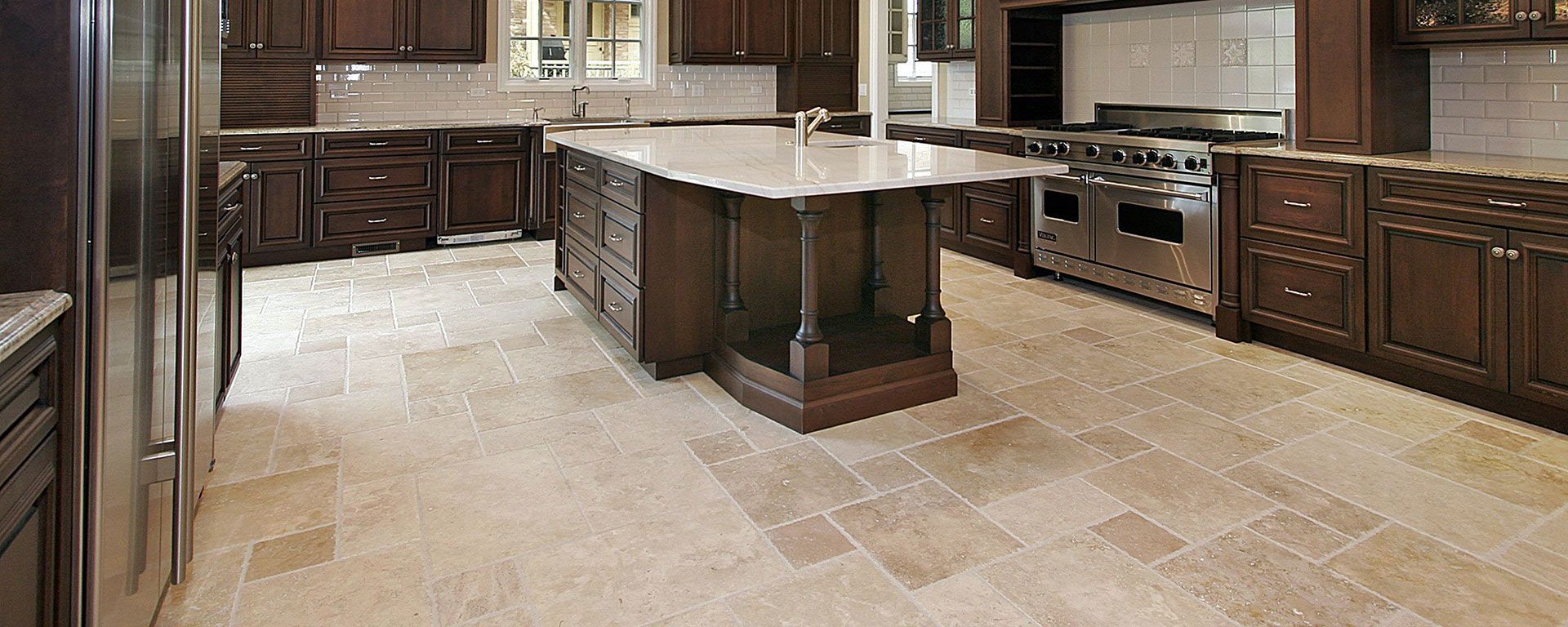 A large kitchen with dark wood cabinets, stainless steel appliances, and a central island with a countertop.