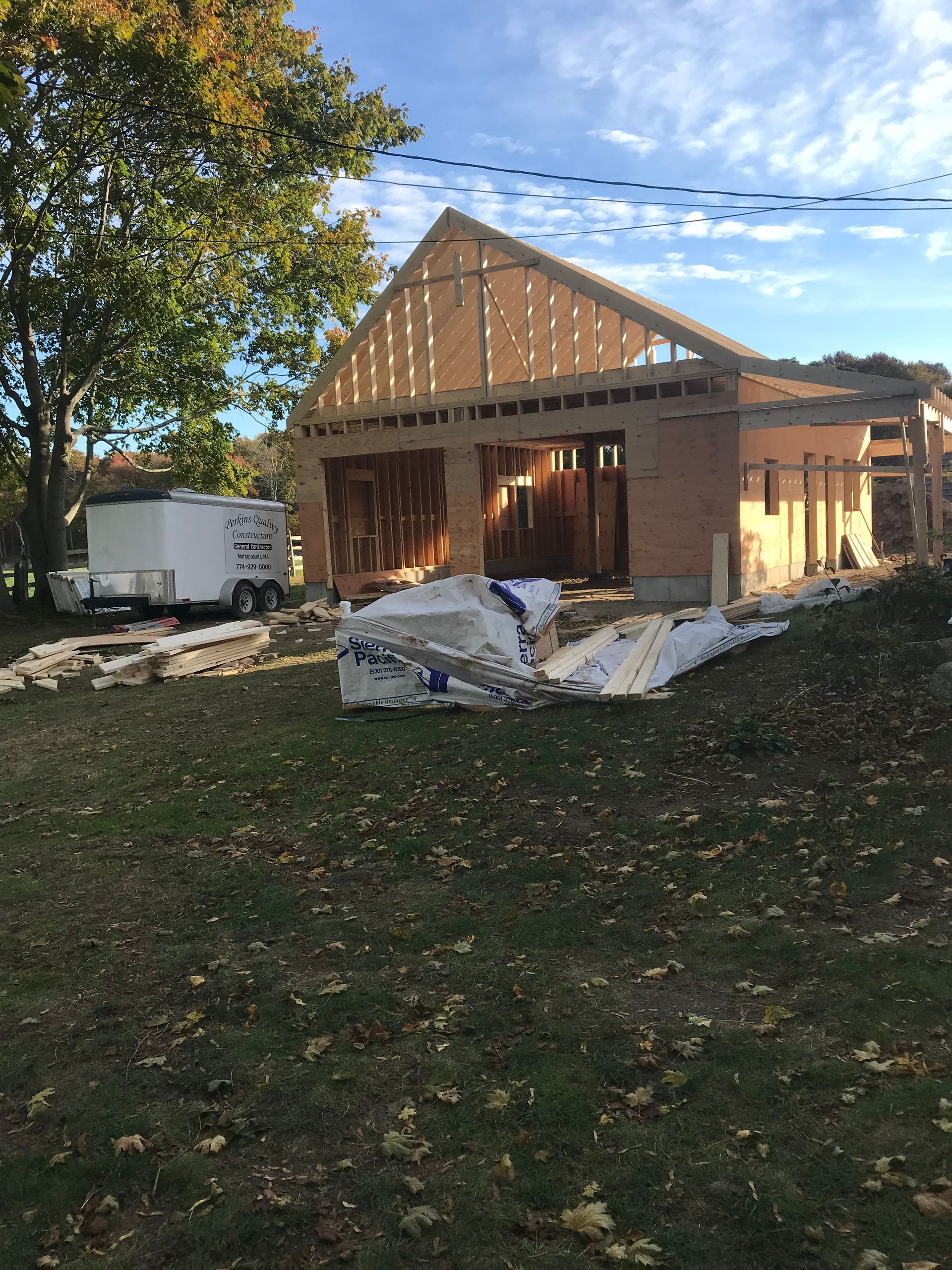 A white trailer is parked in front of a house under construction.