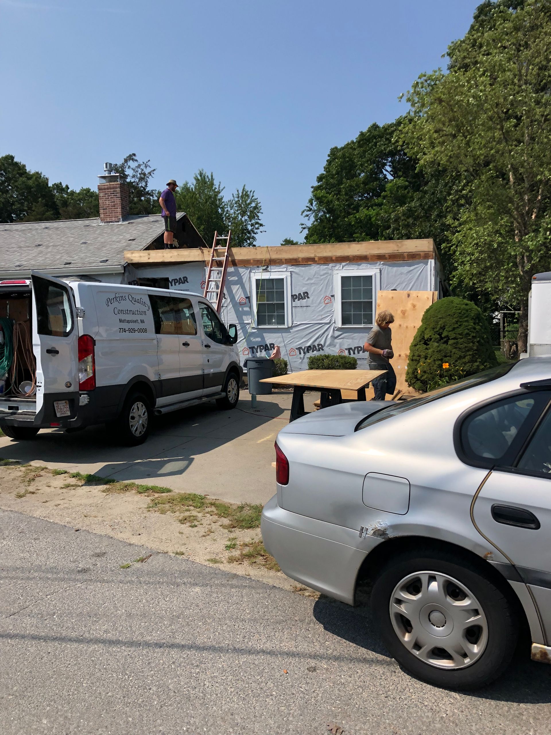 A van and a car are parked in front of a house.