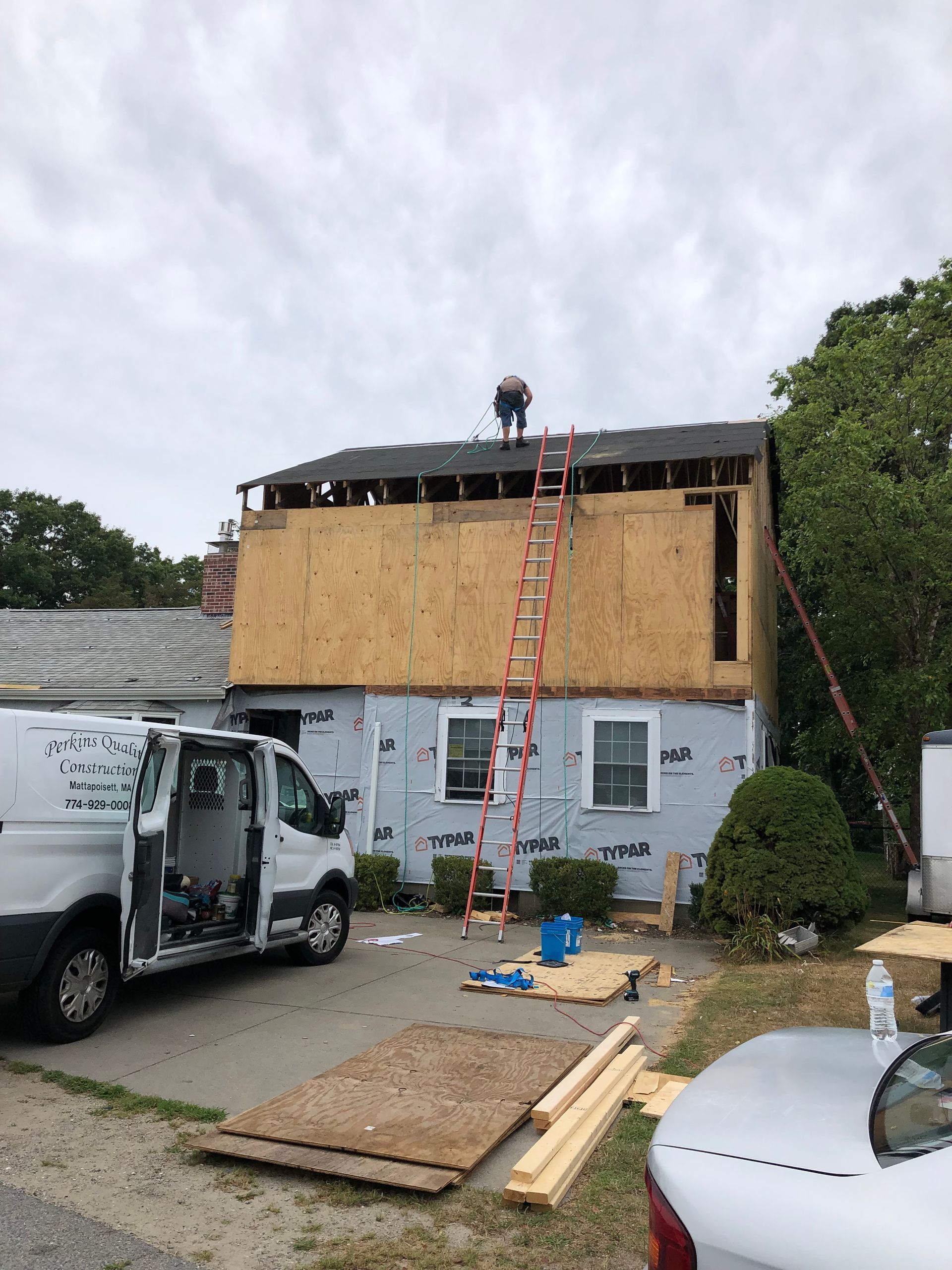 A white van is parked in front of a house under construction.