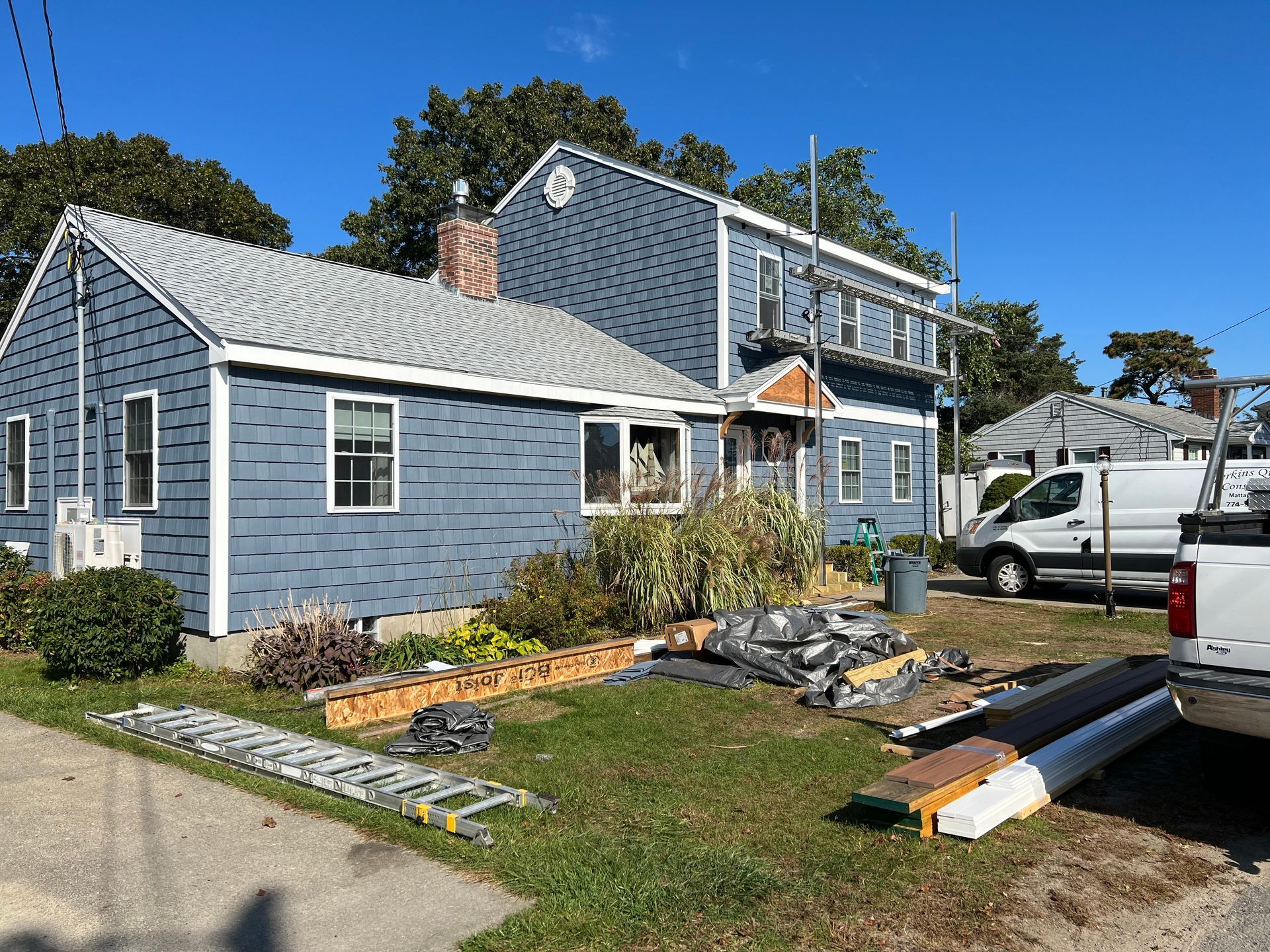 A blue house with a white roof is being remodeled.