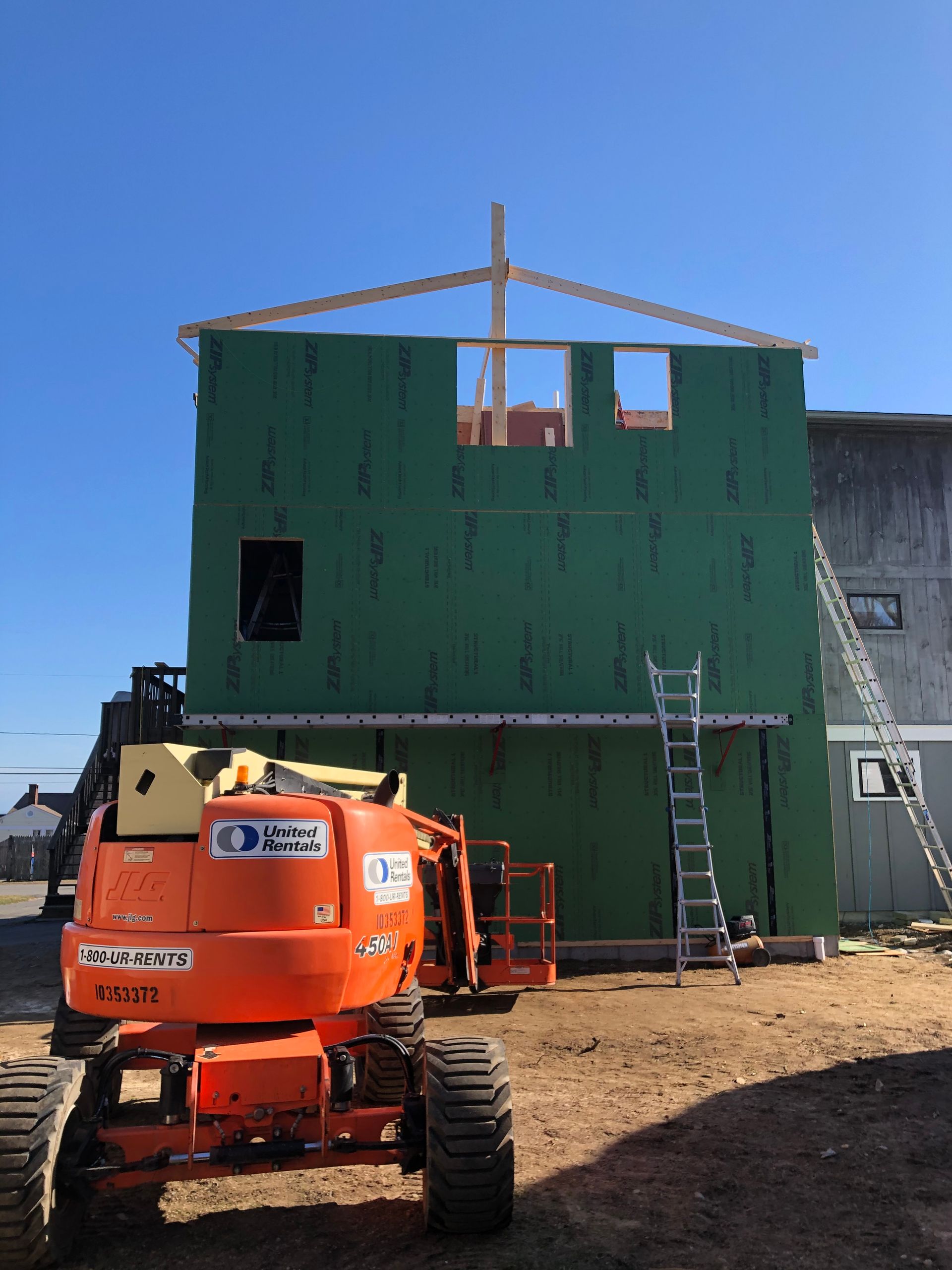 An orange construction vehicle is parked in front of a building under construction.