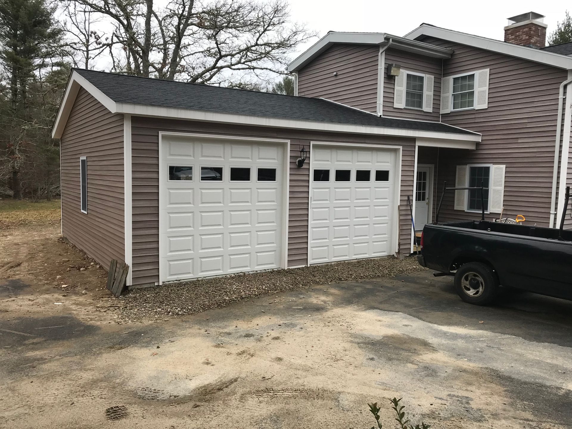 A truck is parked in front of a house with two garage doors.