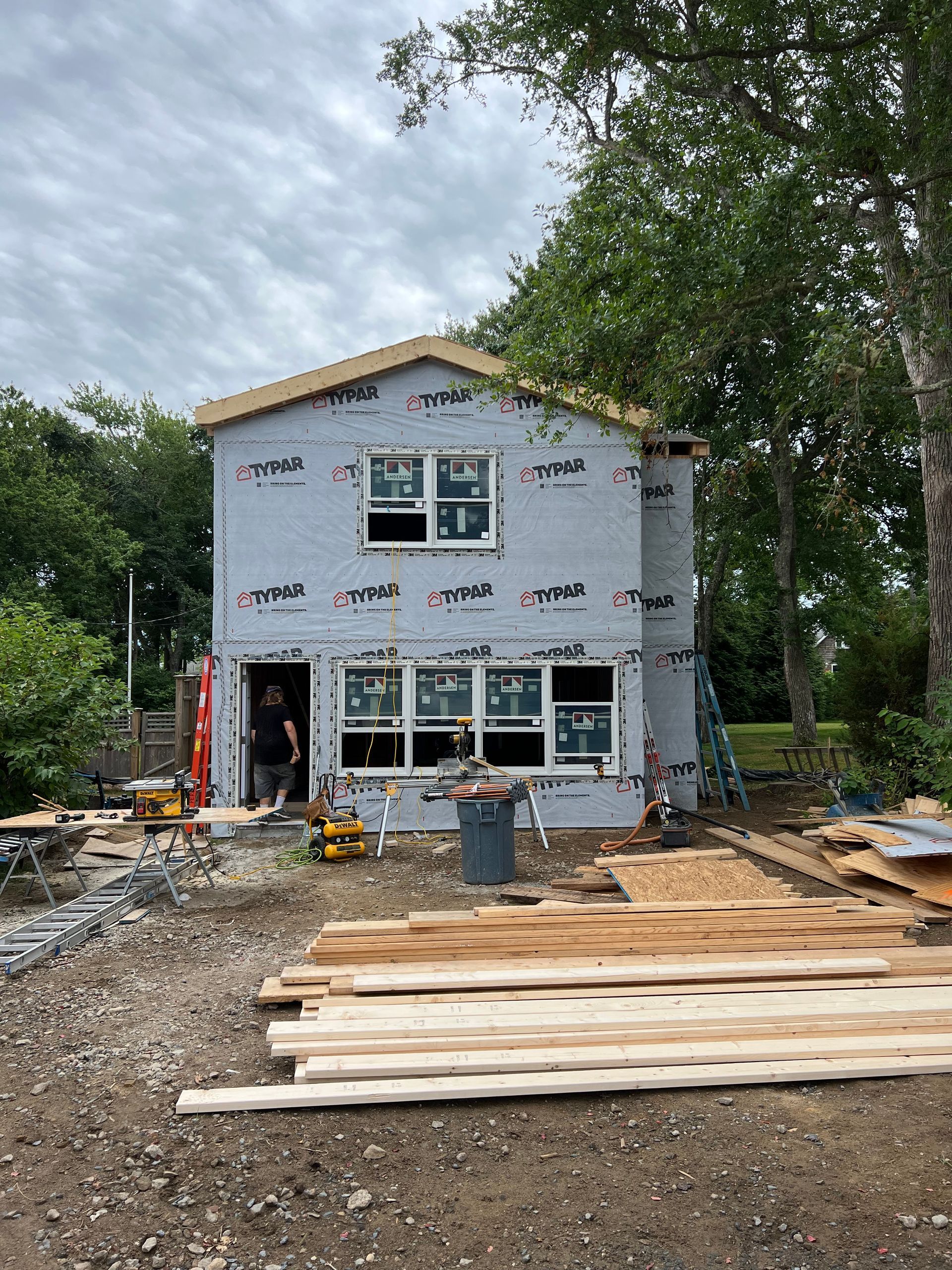A house is being built with a lot of wood in front of it.