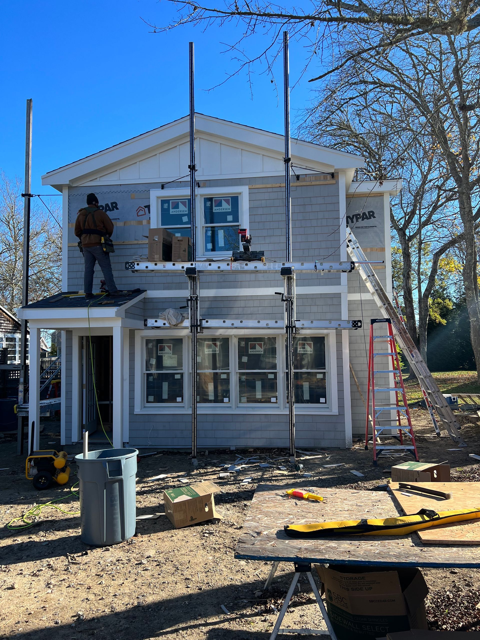 A man is standing on the roof of a house under construction.