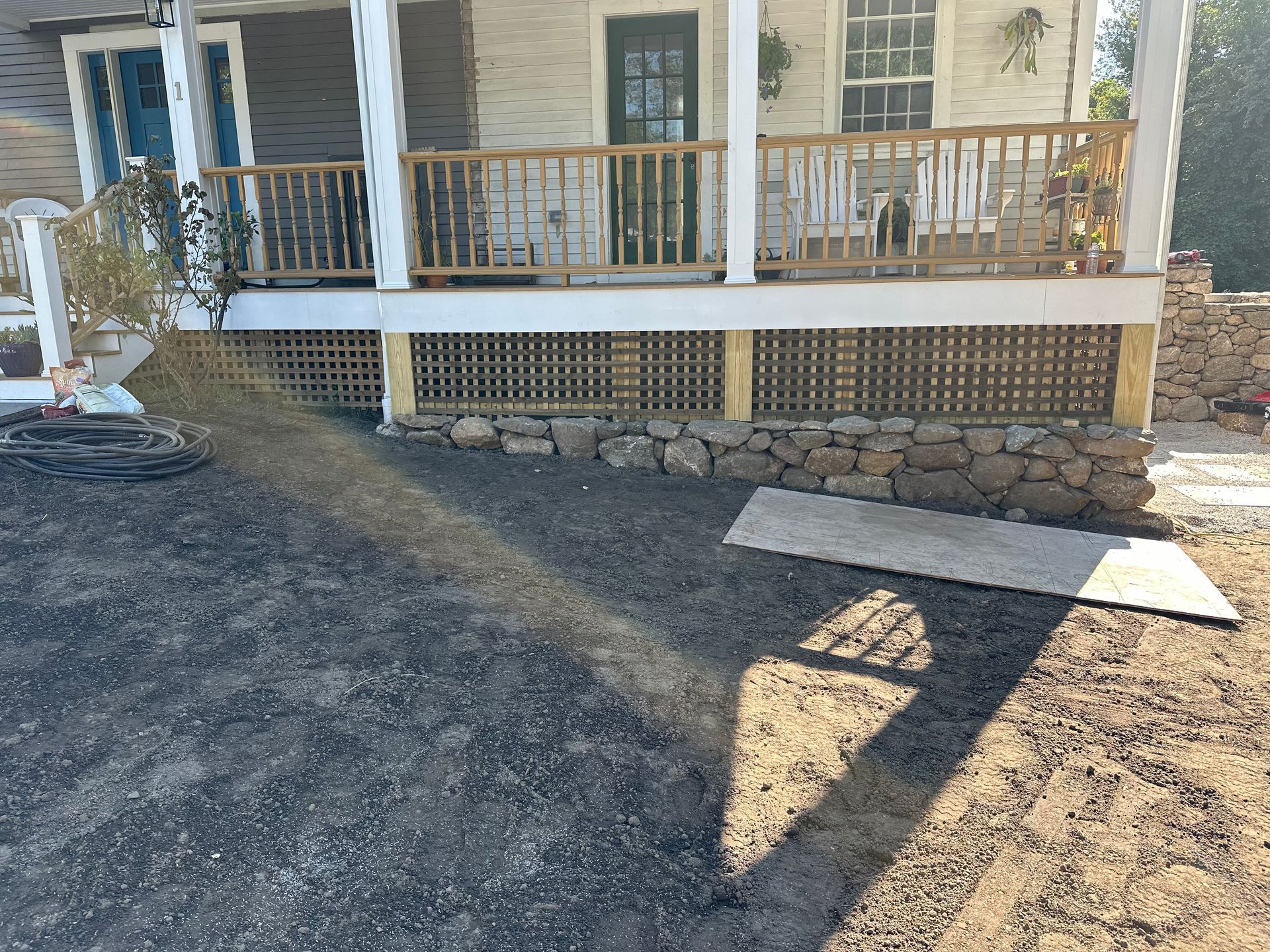 The front of a house with a porch and a stone wall.