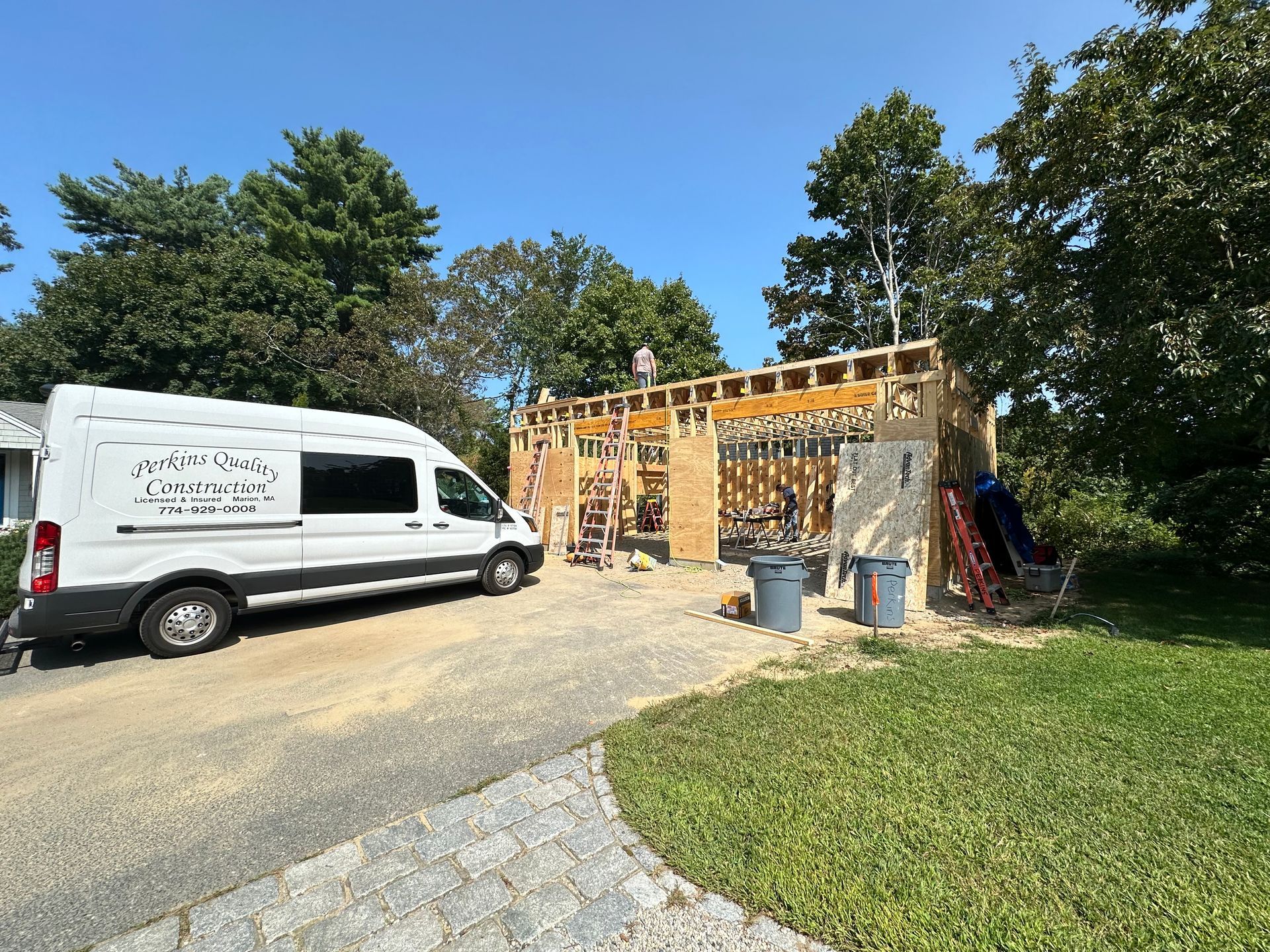 A white van is parked in front of a house under construction.