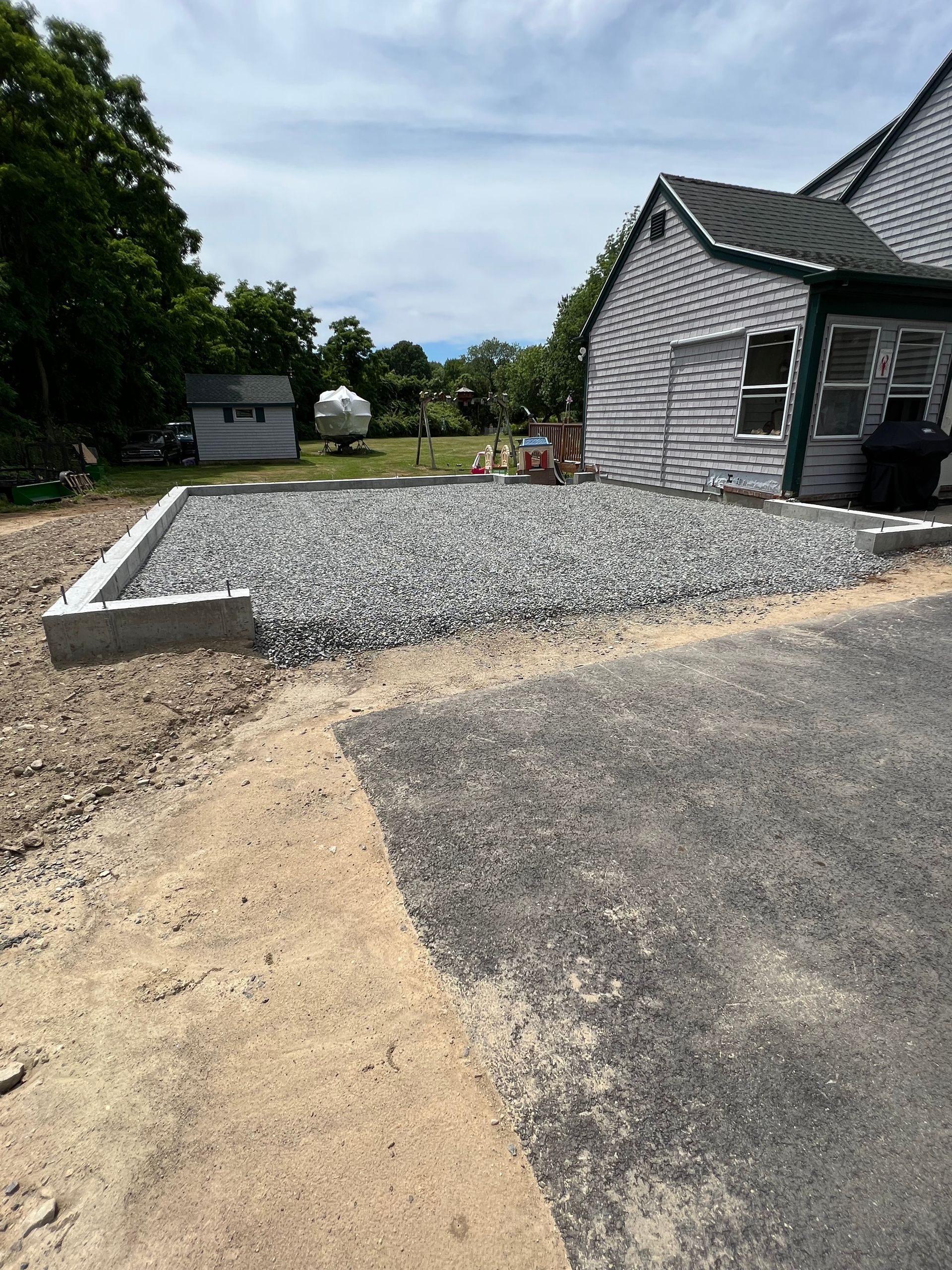 A gravel driveway is being built in front of a house.