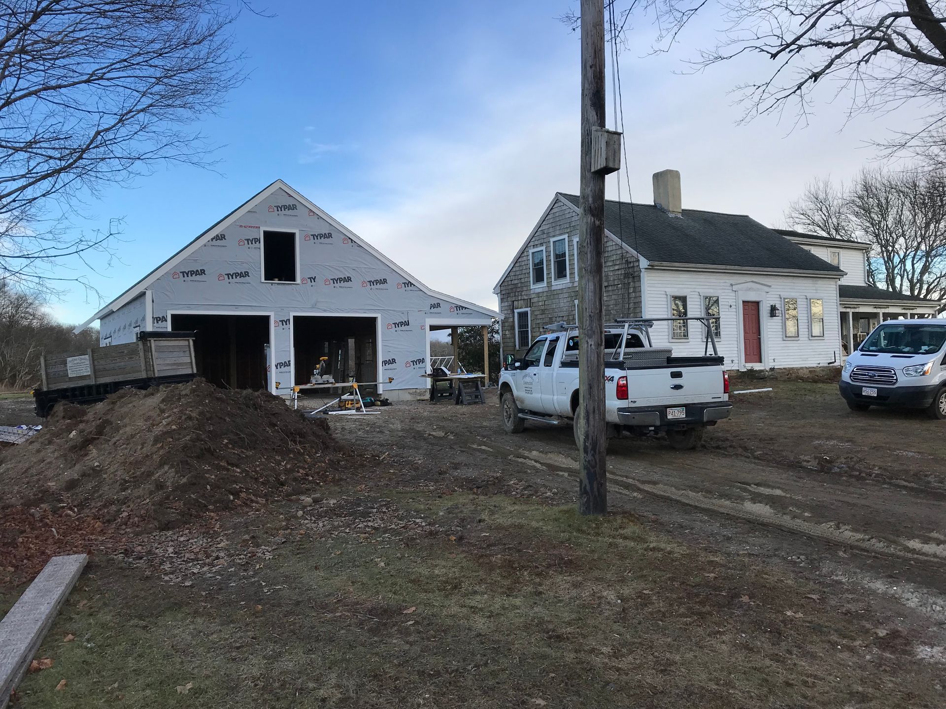 A white truck is parked in front of a house under construction.