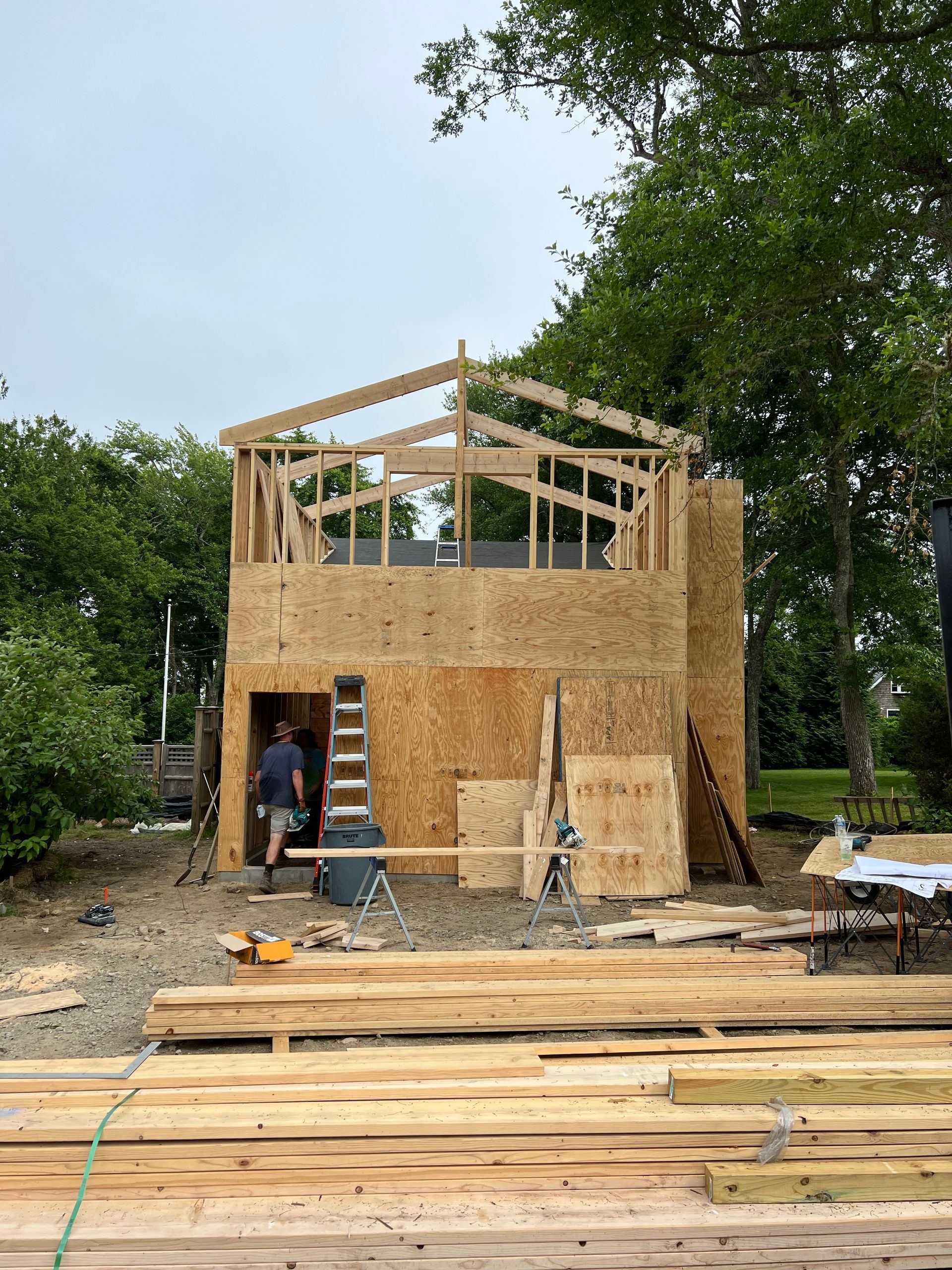 A man is standing in front of a wooden building under construction.