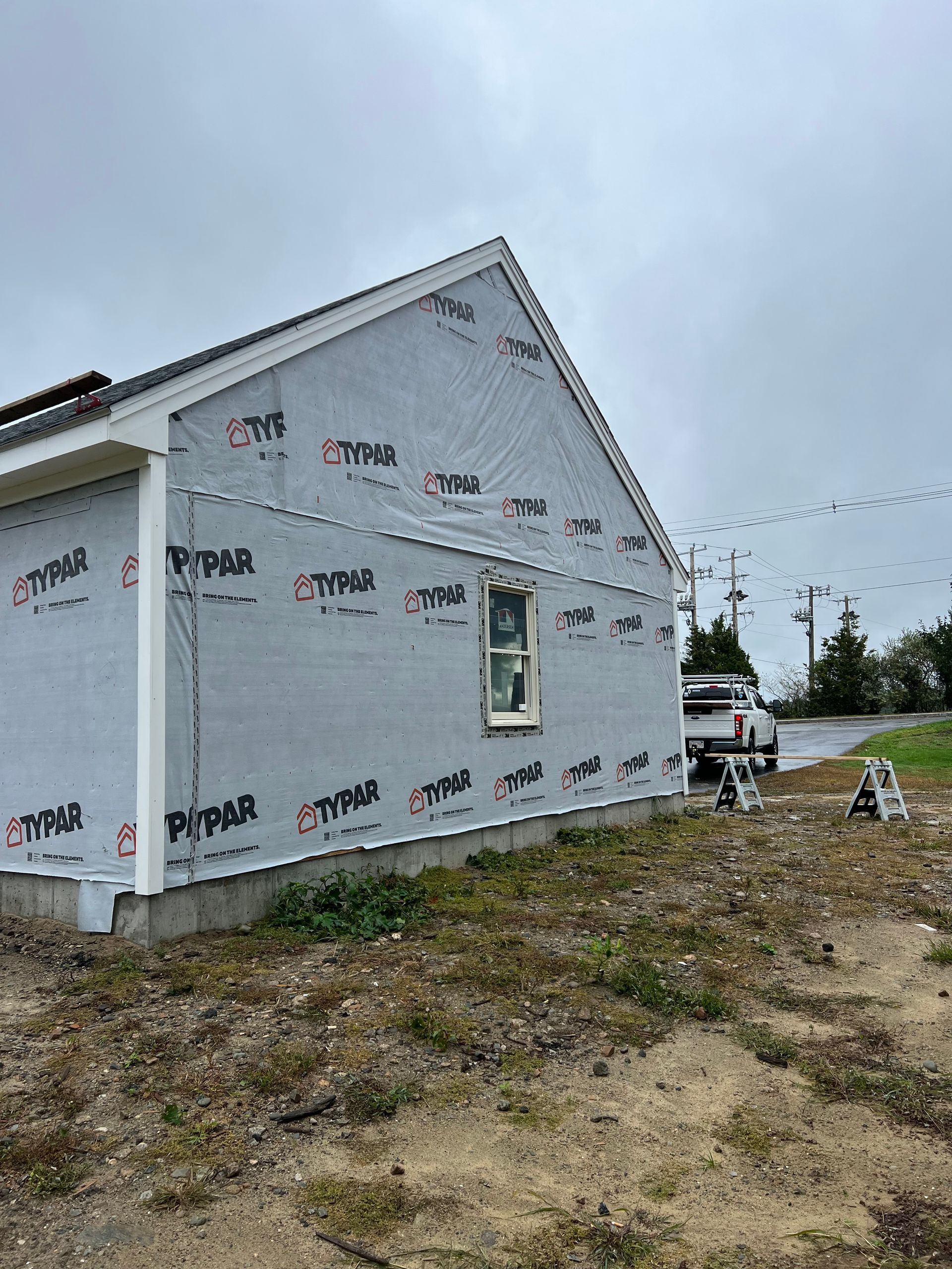A house is being built in a field with a truck parked in front of it.