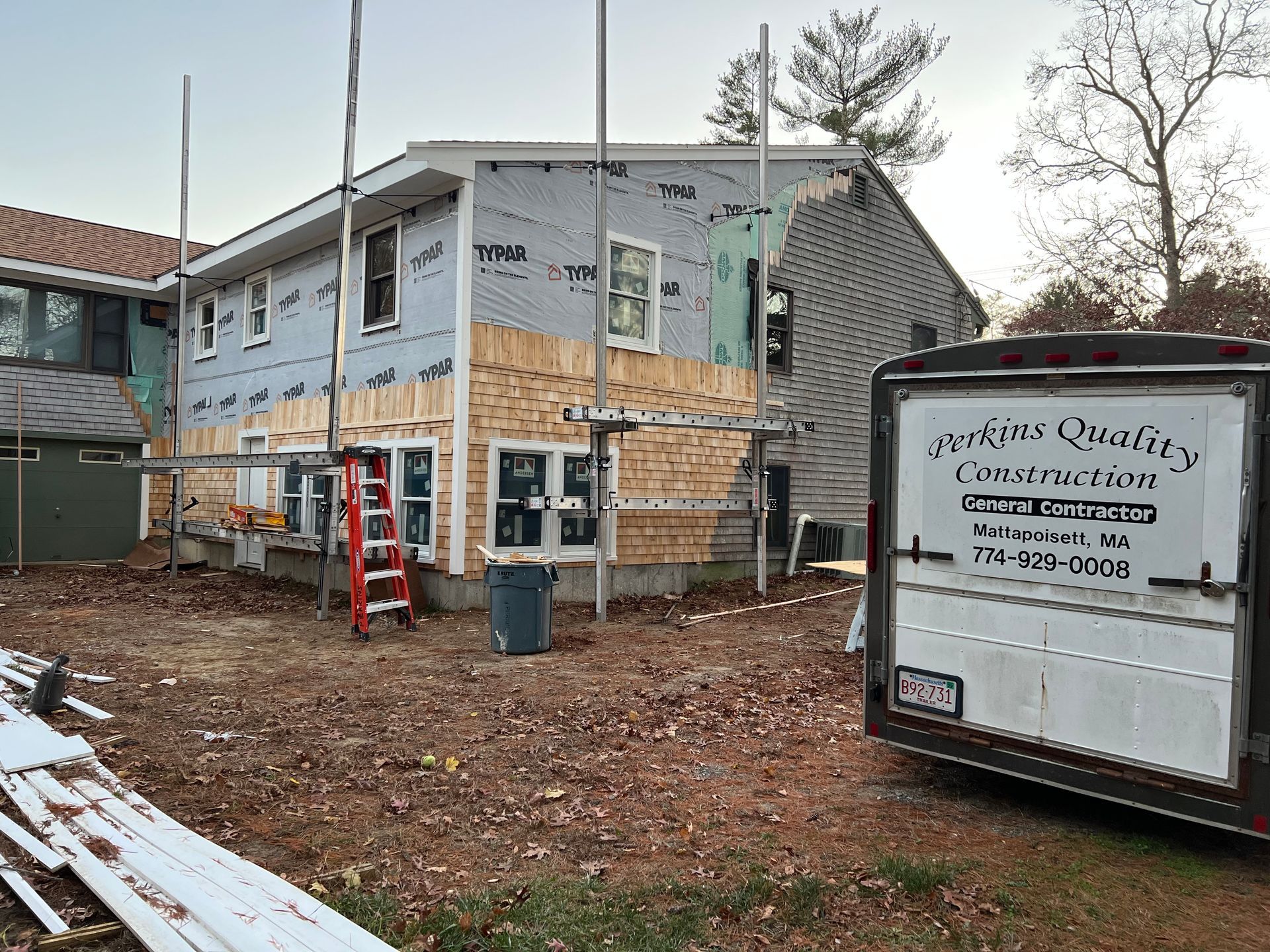 A house is being remodeled and a trailer is parked in front of it.