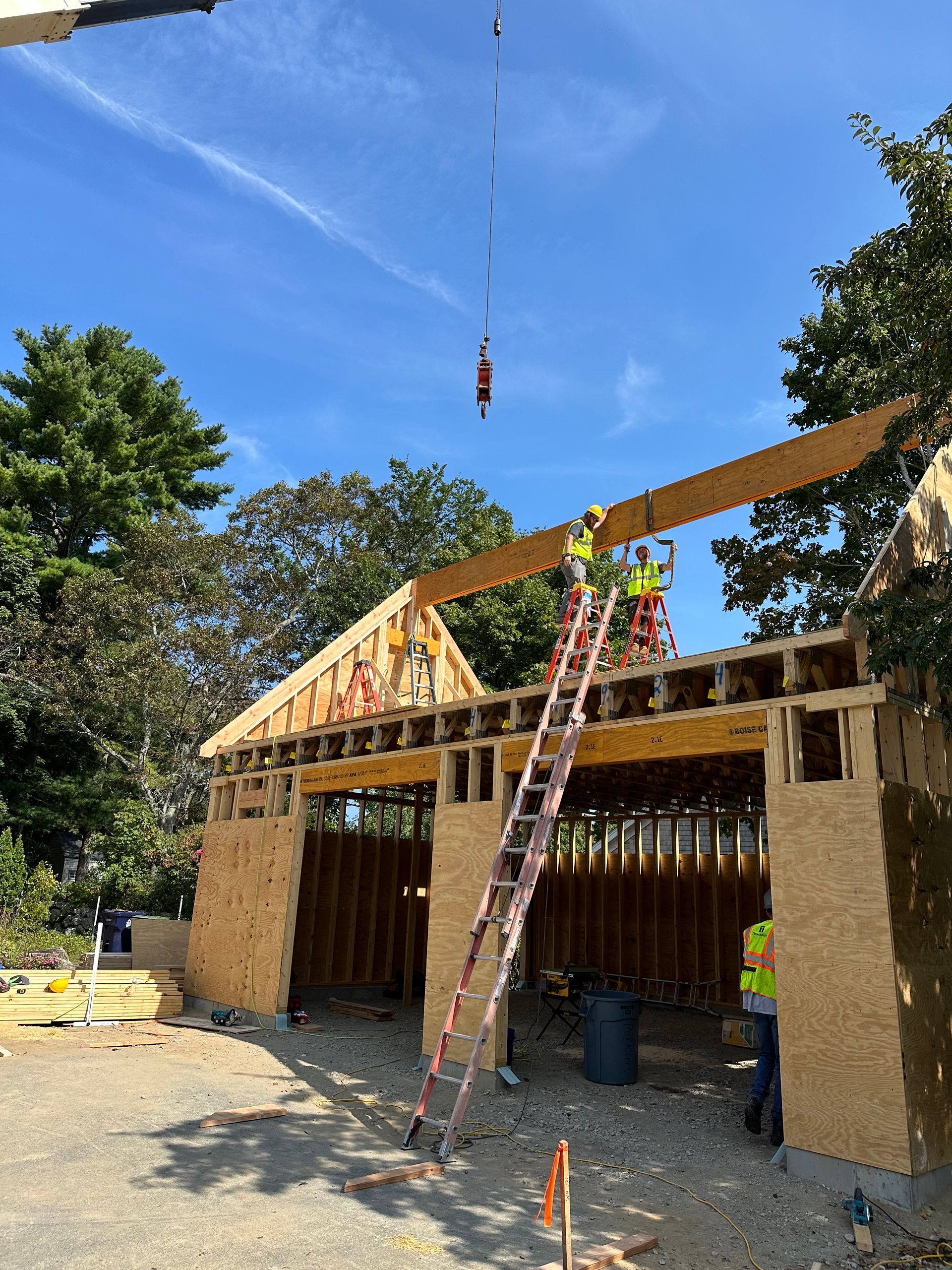 A crane is lifting a wooden beam over a building under construction.