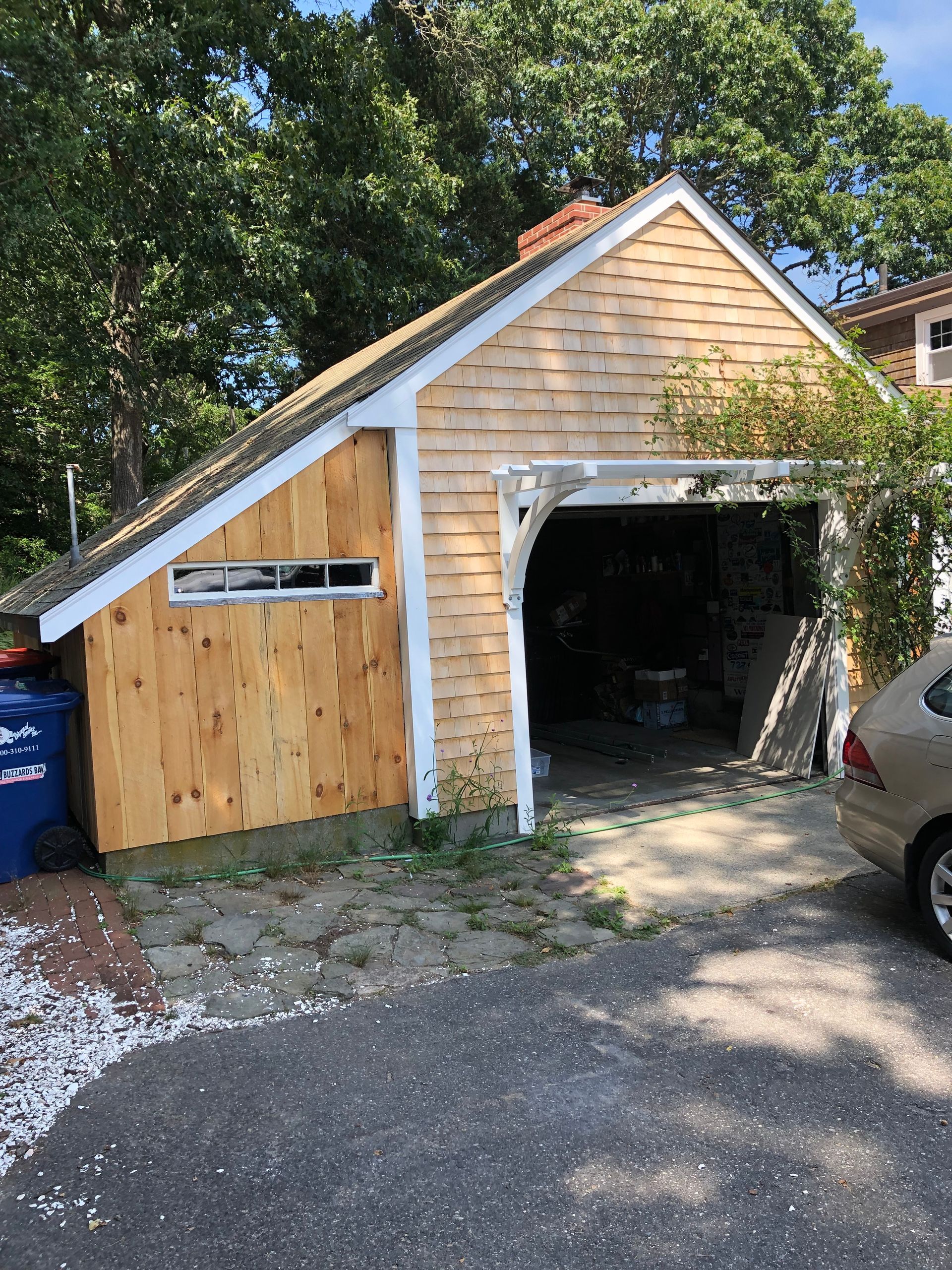 A car is parked in front of a wooden garage.