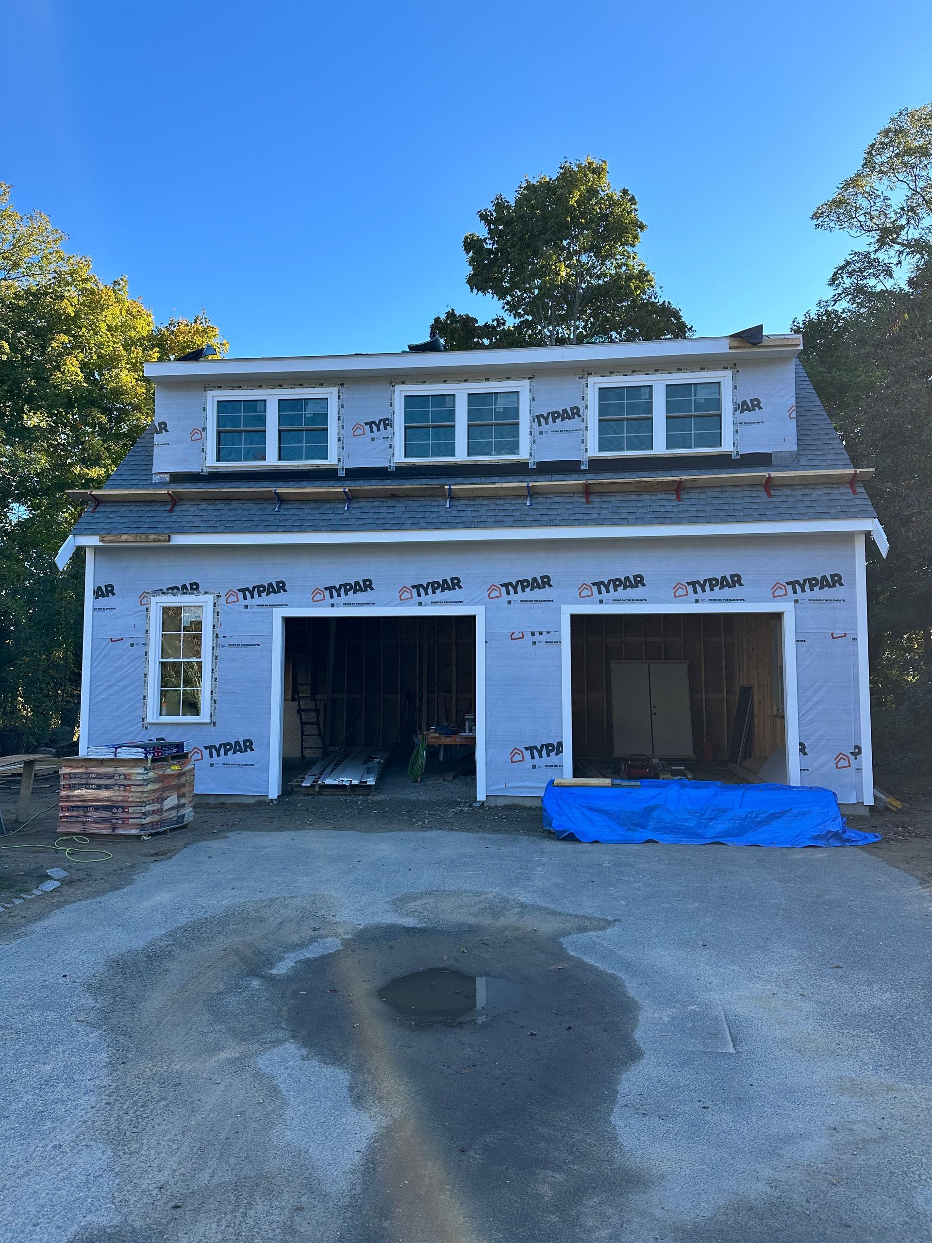 A garage under construction with a blue tarp on the ground